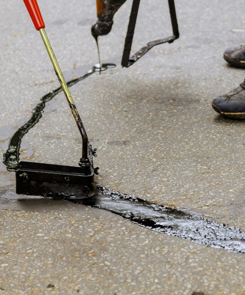 Asphalt crack sealing being applied to pavement surface
