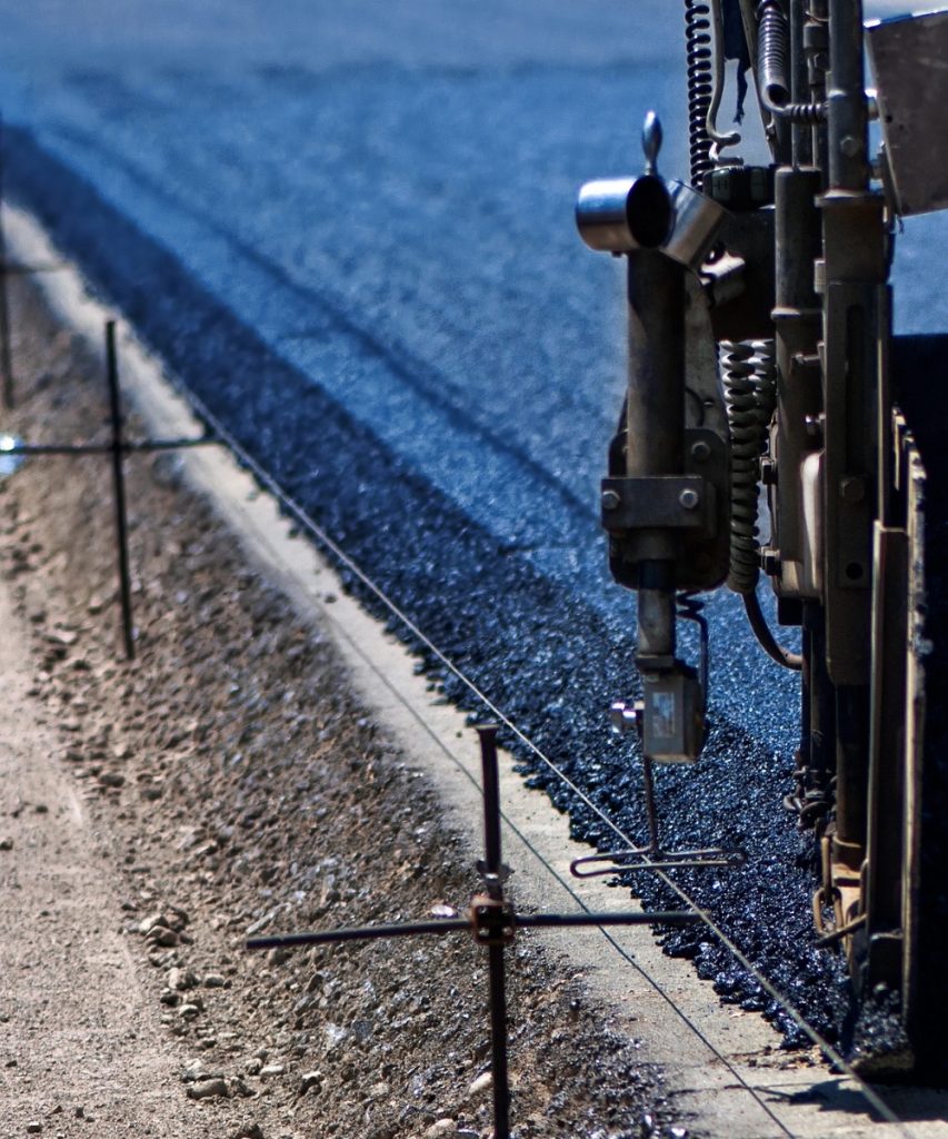 Fresh asphalt paving with road construction equipment