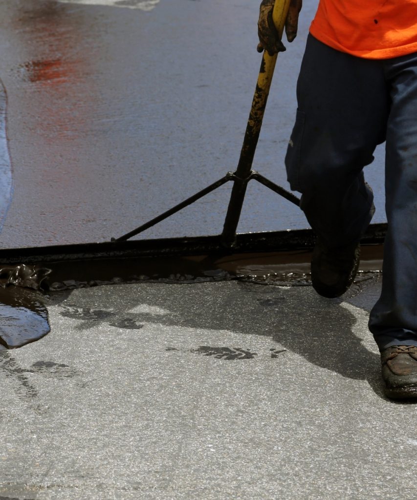 Squeegee sealcoating asphalt surface for even coverage